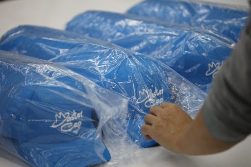 Worker placing caps into clear polybags for primary protection