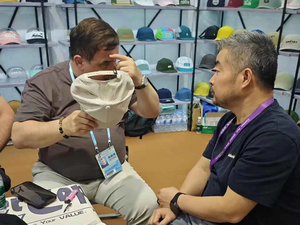 International buyer inspecting the inside stitching and mesh quality of a MasterCap hat with our founder Joe